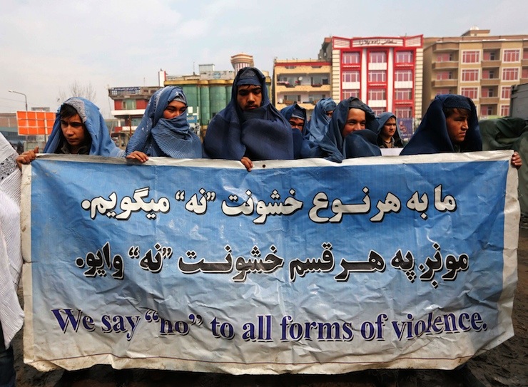 Male Afghan women's rights activists wearing burqas hold up banner to show solidarity to Afghan women ahead of International Women's Day in Kabul