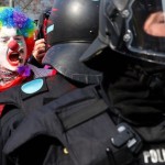 An anti-capitalist protester dressed as a clown shouts behind policemen near the ECB building before the official opening of its new headquarters in Frankfurt