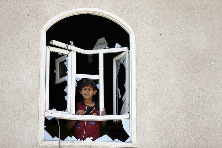 Boy looks through a window of his home damaged by an air strike near Sanaa Airport