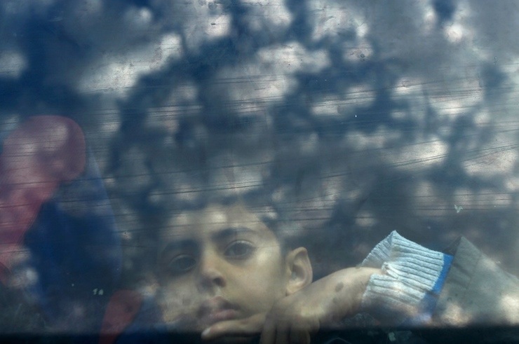 A Palestinian boy looks out a bus window as he waits with his family to cross into Egypt, at the Rafah crossing between Egypt and the southern Gaza Strip
