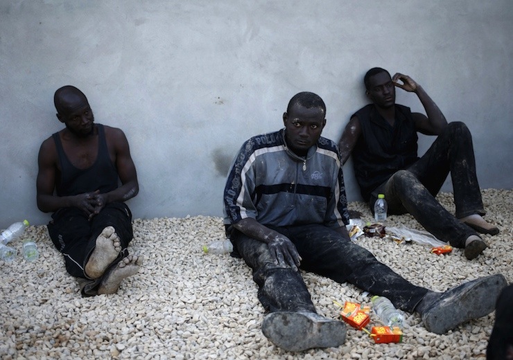 Illegal migrants sit in a coastal police base in Tripoli
