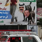 A taxi driver looks out from his car in front of defaced images of U.S. President Barack Obama with Qatar's Emir Sheikh Hamad bin Khalifa al-Thani and Turkey's Prime Minister Tayyip Erdogan in downtown Cairo