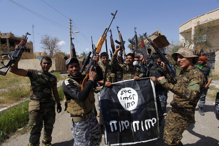 Iraqi security forces and Shi'ite paramilitary fighters hold an Islamist State flag, which they pulled down in Tikrit