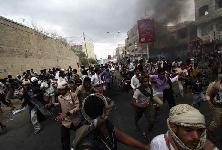 Anti-Houthi protesters run as pro-Houthi police troopers open fire in the air to disperse them in Yemen's southwestern city of Taiz