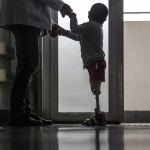 Hospital staff helps a boy stand with his prosthetic legs at a hospital in Wuhan