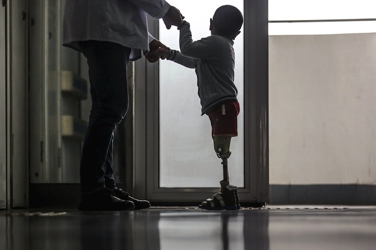 Hospital staff helps a boy stand with his prosthetic legs at a hospital in Wuhan
