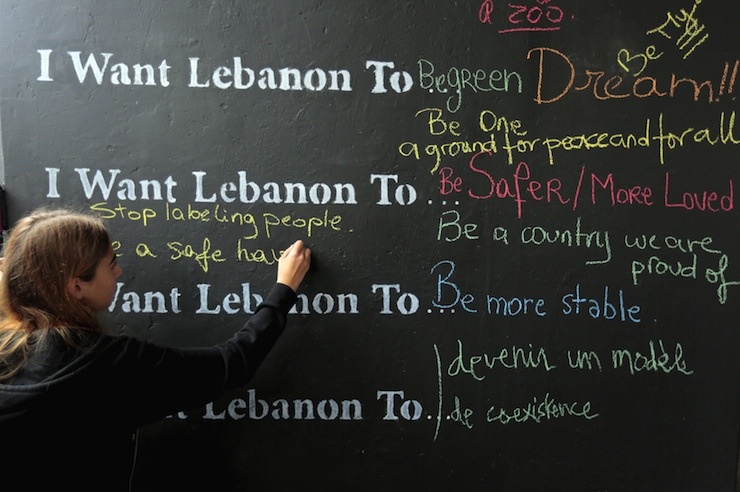 A Lebanese student writes on a wall during an event to mark the 40th anniversary of Lebanon's civil war (1975-1990) along a street of Beirut's former green-line