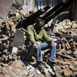 Man sits on the rubble of his damaged house following Saturday's earthquake in Bhaktapur, Nepal