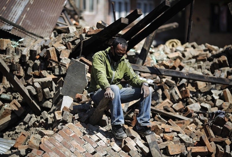 Man sits on the rubble of his damaged house following Saturday's earthquake in Bhaktapur, Nepal