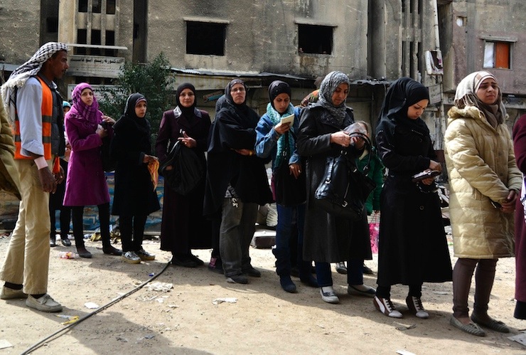 Residents queue up to receive humanitarian aid at the Palestinian refugee camp of Yarmouk, in Damascus