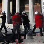 Riot police stand guard with red paint on their shields, thrown by anti-establishment protesters during a demonstration against high security prisons in Athens