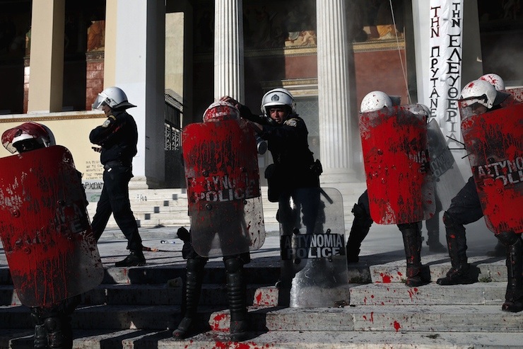Riot police stand guard with red paint on their shields, thrown by anti-establishment protesters during a demonstration against high security prisons in Athens