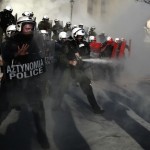 Riot police officer uses pepper spray against anti-establishment protesters during a demonstration against high security prisons in Athens