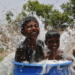 Boys sit in a plastic container filled with water as they cool themselves on the outskirts of Ahmedabad