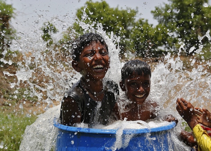 Boys sit in a plastic container filled with water as they cool themselves on the outskirts of Ahmedabad