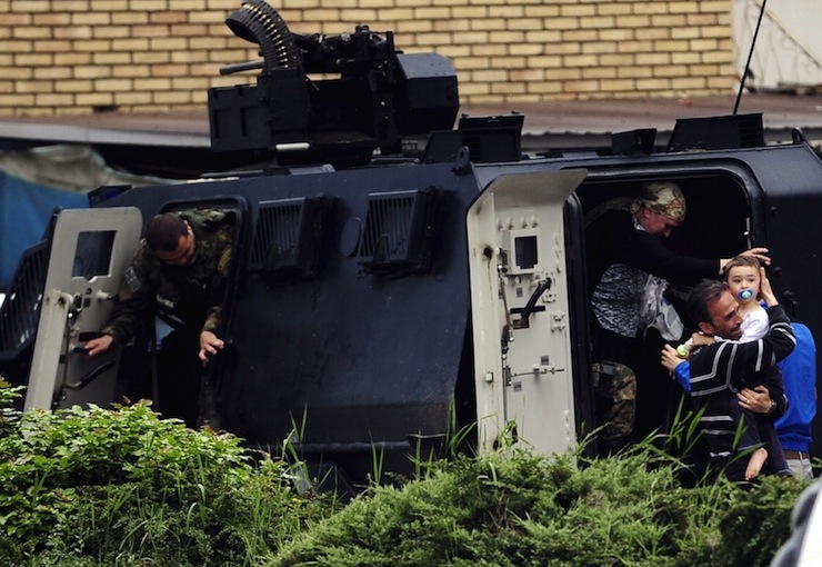 People are evacuated with an armoured vehicle near a police checkpoint in Kumanovo