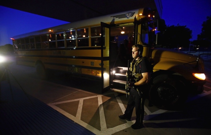 A police officer stands near a school bus used to evacuate attendees of the Muhammad Art Exhibit and Contest after a shooting, in Garland, Texas