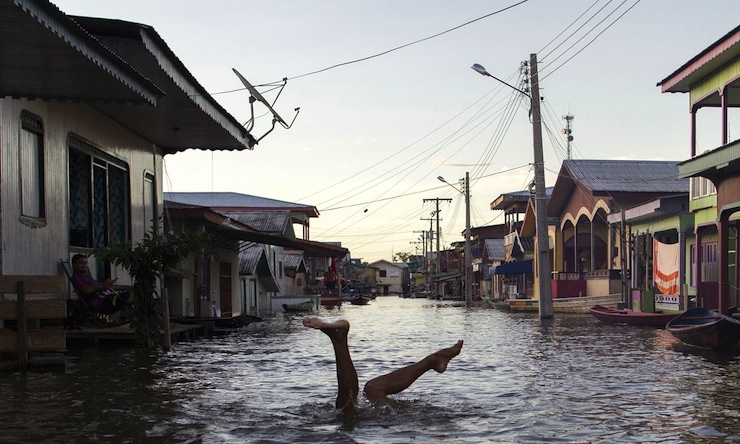 A child jokes in a street flooded by the rising Rio Solimoes, one of the two main branches of the Amazon River, in Anama, Amazonas state, Brazil June 3, 2015. According to the state Civil Defense, more than 250,000 people were affected in the State with strong rains. Picture taken on June 3, 2015. REUTERS/Bruno Kelly       TPX IMAGES OF THE DAY
