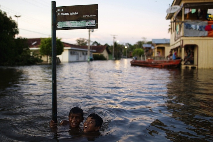 Children joke in a street flooded by the rising Rio Solimoes, one of the two main branches of the Amazon River, in Anama, Amazonas state, Brazil June 3, 2015. According to the state Civil Defense, more than 250,000 people were affected in the State with strong rains. Picture taken June 3, 2015. REUTERS/Bruno Kelly       TPX IMAGES OF THE DAY