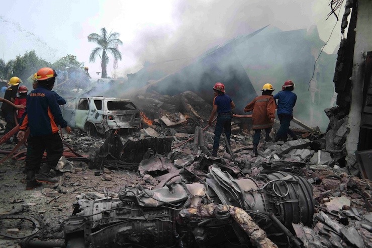 Firemen attempt to extinguish the fire surrounding the wreckage of an Indonesian military transport plane after it crashed in the North Sumatra city of Medan