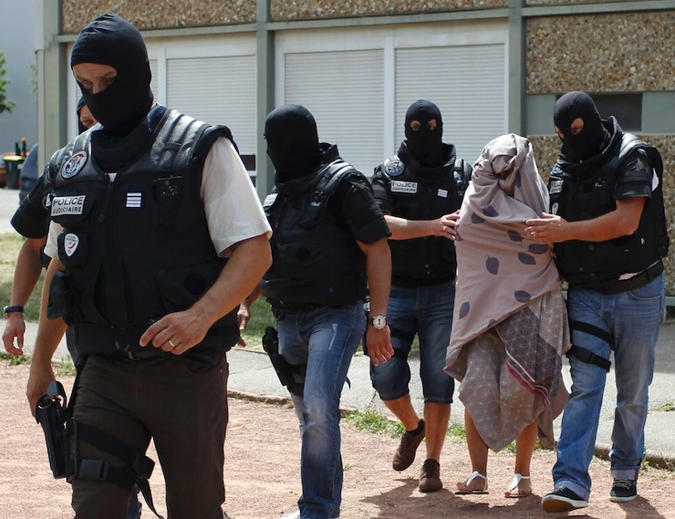 French special Police forces escort a woman from a residential building during a raid in Saint-Priest