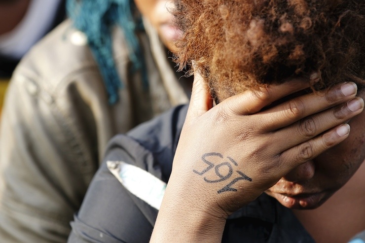 The identification number is seen written on woman's hand as she rests with more than 1,000 migrants after they are disembarked from the British assault ship HMS Bulwark at the Sicilian port of Catania after being rescued at sea