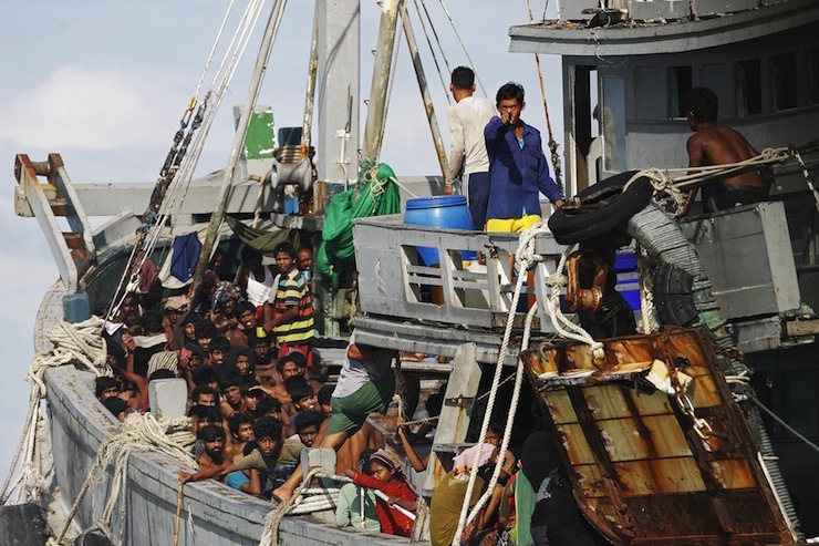 A Myanmar military officer gestures from a boat packed with migrants off Leik Island in the Andaman Sea