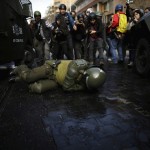 A policeman lies on the ground during a clash with students demonstrating to demand changes in the education system, in Santiago
