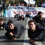 Students crawl on the ground during a protest against the government to demand changes in the education system in Valparaiso