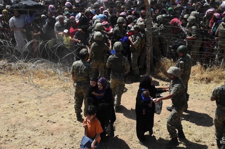 Turkish soldiers help Syrian refugees as they cross into Turkey on the Turkish-Syrian border, near the southeastern town of Akcakale in Sanliurfa province, Turkey