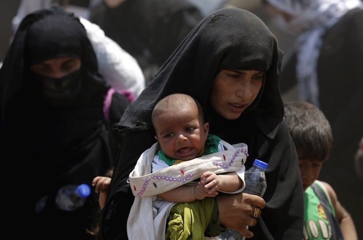 Syrian refugee women cross into Turkey with their children at the Akcakale border gate in Sanliurfa province