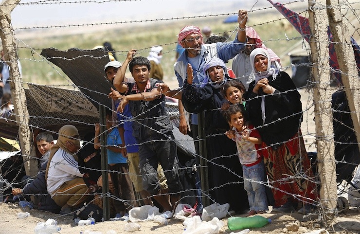 Syrian refugees wait behind the border fences to cross into Turkey at Akcakale border gate in Sanliurfa province, Turkey