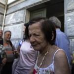 People, most of them pensioners, gather outside a closed National Bank branch at the bank's headquarters in Athens