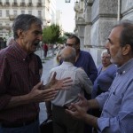 People, most of them pensioners, argue with a staff member of a closed National Bank branch at the bank's headquarters in Athens