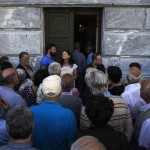 People, most of them pensioners, argue with a staff member outside a closed National Bank branch at the bank's headquarters in Athens