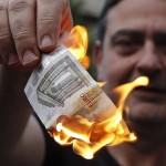 An anti-austerity protester burns a euro note during a demonstration outside the European Union (EU) offices in Athens