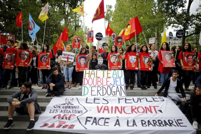 Members of the Kurdish community in France hold posters depicting victims of a Monday's bomb attack in Turkey during a demonstration in Paris