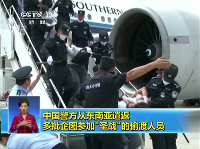 Still image taken from video shows people being deported from Thailand being brought off an airplane by police at an unidentified location in China