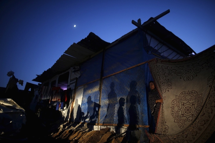 Palestinian woman looks out her makeshift shelter near her house that witnesses said was destroyed by Israeli shelling during 50-day war last summer, in Beit Hanoun town in northern Gaza Strip