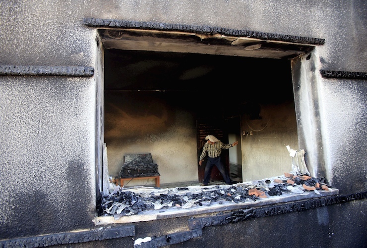 Palestinian man inspects a house that was badly damaged in a suspected attack by Jewish extremists on two houses at Kafr Duma village near Nablus