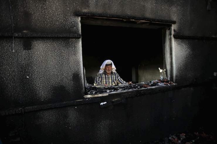 A Palestinian man looks out a house that was badly damaged from a suspected attack by Jewish extremists on two houses at Kafr Duma village near Nablus