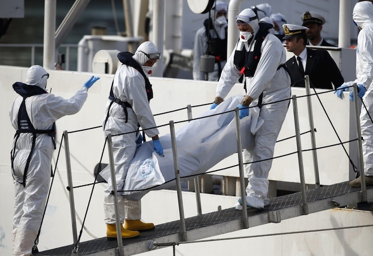 Italian coastguard personnel in protective clothing carry the body of a dead immigrant off their ship Bruno Gregoretti in Senglea