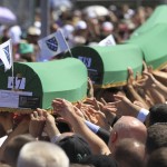 People carry coffins to graves at the Memorial Center Potocari, near Srebrenica