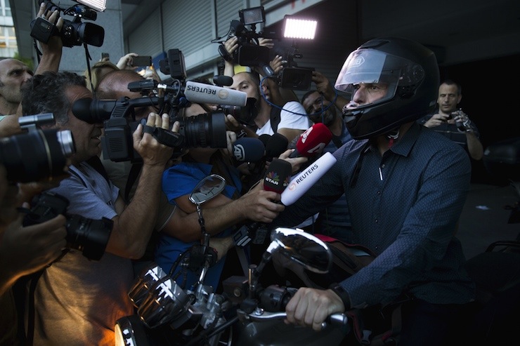 Greek Finance Minister Varoufakis talks to the media as he leaves the Finance Ministry building on his motorbike in Athens