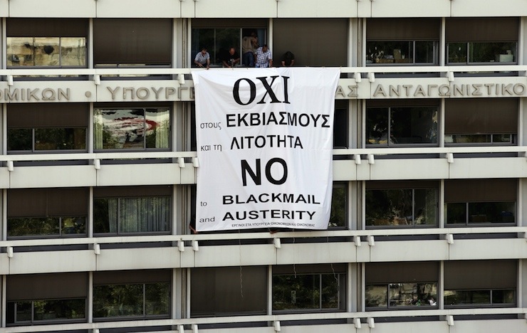 Employees of the Ministry of Finance and National Economy stand by a banner unfolded from a balcony of the Finance Ministry in Athens