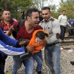 Migrant reacts as he carries a child during clashes with Macedonian police at the Greek-Macedonian border