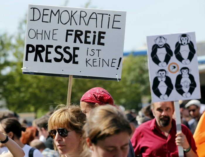 Demonstrators hold up placards during a rally to protest against a criminal complaint by the domestic intelligence agency, the Office for the Protection of the Constitution in Berlin