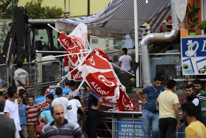 People stand among debris after an attack on a nearby police station in Istanbul, Turkey, August 10, 2015. Overnight, a vehicle laden with explosives was used in the attack on the police station in the Istanbul district of Sultanbeyli at around 01:00 on Monday (2200 GMT on Sunday), injuring three police officers and seven civilians, police said. REUTERS/Huseyin Aldemir