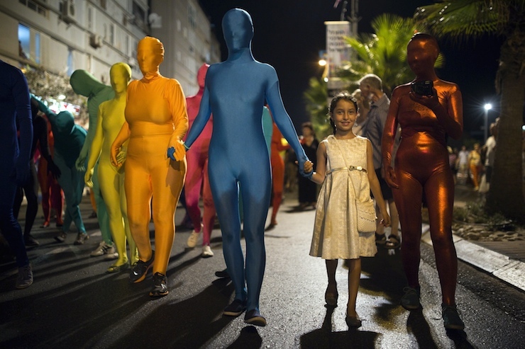 A group of people wearing full solid-coloured bodysuits walk along a promenade as they take part in a street art performance in Bat Yam, near Tel Aviv, Israel August 29, 2015. Some 40 people participated on Saturday in the performance, initiated by a group of artists called Prizma Ensemble, as part of the city's annual international street art and street theatre festival. The group says the performance deals with concepts of identity and movement in public spaces. REUTERS/Amir Cohen TPX IMAGES OF THE DAY
