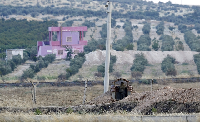 A Turkish soldier stands guard at the Turkish-Syrian border in Karkamis, bordering with the Islamic State-held Syrian town of Jarablus, in Gaziantep province, Turkey, August 1, 2015. Karkamis is a Turkish town of 10,500 people that sits directly opposite the border post. Shut for more than a year, the military sealed the crossing with a breeze block wall a few months ago. Behind it, just inside Syria, the black flag of Islamic State flaps in the breeze. Karkamis lies on the northeastern edge of a rectangle of Syrian territory some 80 km (50 miles) long, controlled by the radical Islamists. The United States and Turkey hope that by sweeping Islamic State from this border zone, they can deprive it of a smuggling route which has seen its ranks swollen with foreign fighters and its coffers boosted by illicit trade. Picture taken August 1, 2015. REUTERS/Murad Sezer